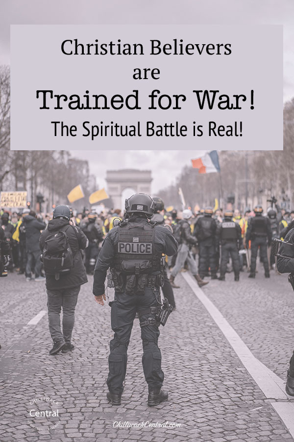 Police, trained for war, are managing crowd control on the street. The text overlay reads "Christian Believers are Trained for War! The Spiritual Battle is Real! 